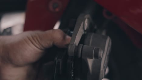 automobile mechanic man replacing and replacement front hydraulic disc brakes pads with caliper on motorcycle