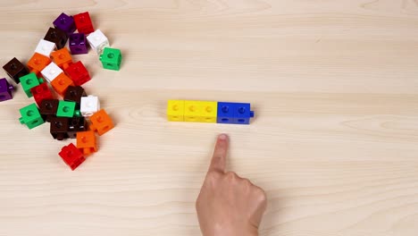 hand organizing cubes on a wooden surface