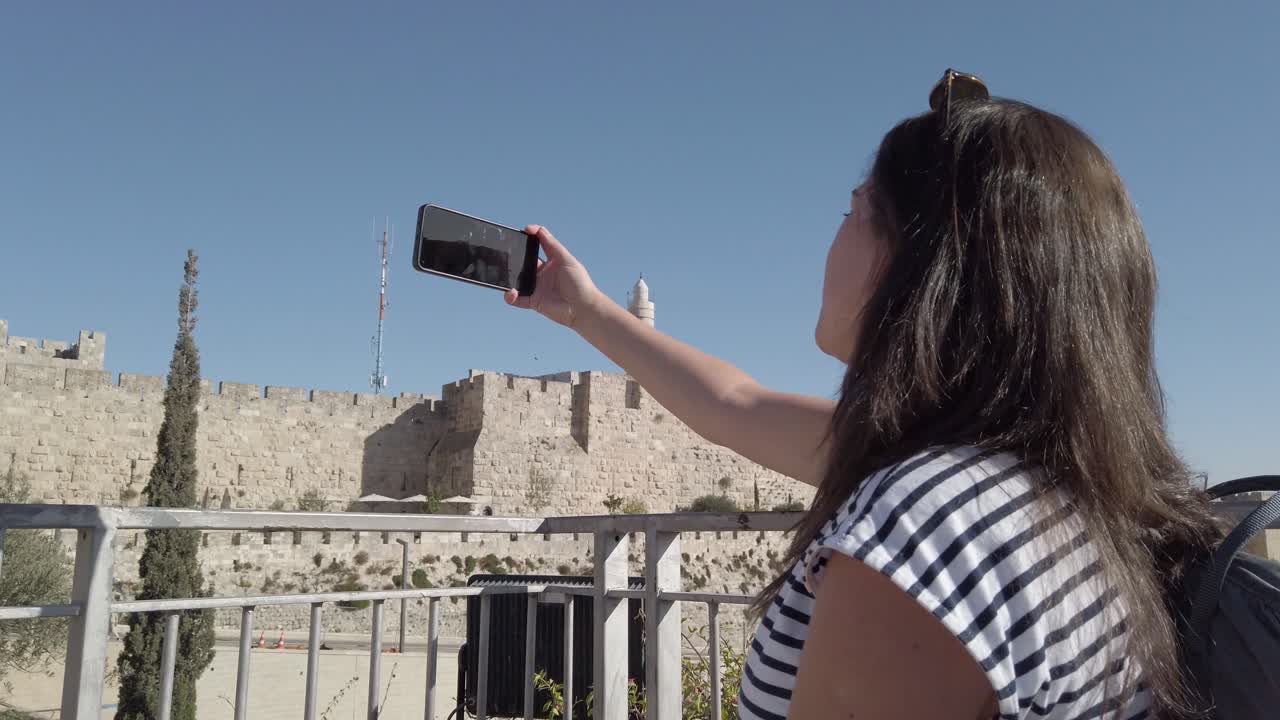 mujer tomando una selfie frente a las murallas de la vieja ciudad de jerusalén
