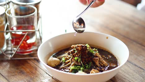 añadiendo especias a un plato de sopa de fideos