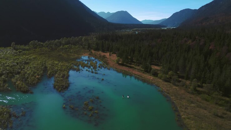 Stand Up Paddle al lago Sylvenstein Speicher, un suggestivo bacino idrico alpino con acqua blu nelle Alpi bavaresi e austriache, che si estende lungo una splendida foresta di alberi vicino al Walchensee