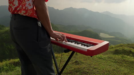 Asian-playing-keyboard-at-mountain-in-Vietnam,-closeup-slow-motion