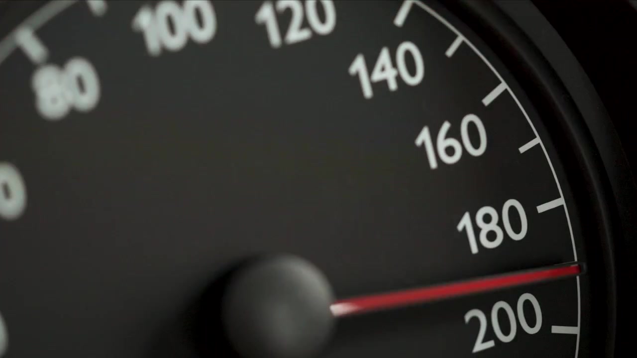 Close-up of a car speedometer with a red needle indicating high speed, with blurred blue police lights in the background. Concept image for speeding, traffic violations, police pursuit, emergency resp