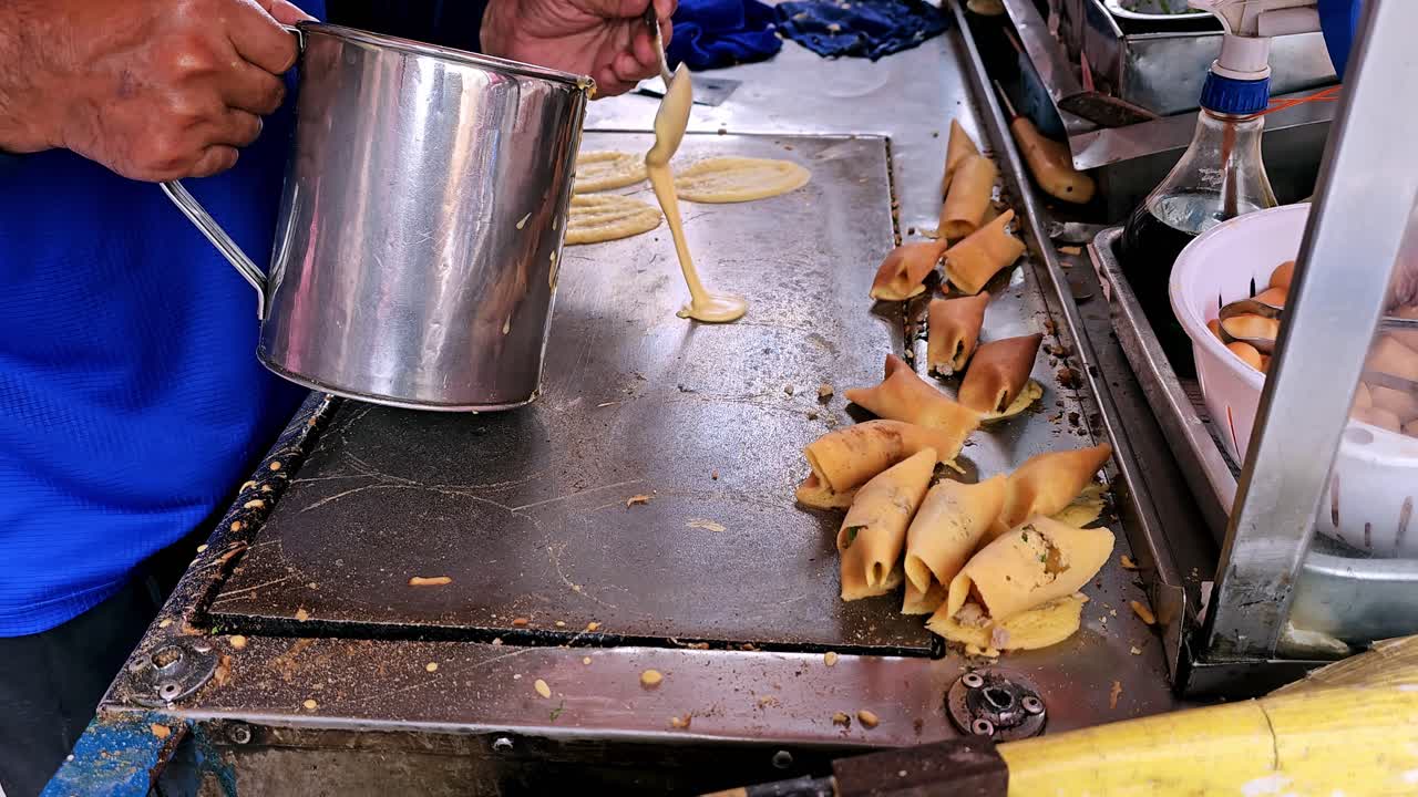 Pedagang membuat jajanan jalanan berupa hidangan penutup Thailand: panekuk gulung dengan isian daging babi, sosis, telur, yang manis