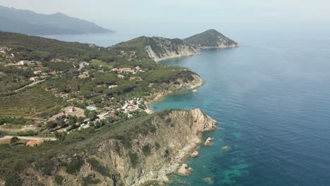 Isla-De-Elba-En-Italia-Costa-Mediterránea-Vegetación-Verde-Aérea-Imágenes-De-La-Playa-Con-Aguas-Azul-Turquesa,-Vuelo-Con-Drone-Turismo-Europeo-Agua-Azul-Cristalina-Del-Italiano
