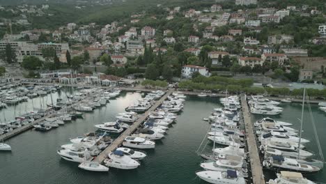 a marina with yachts and boats docked along piers in a coastal town, aerial view