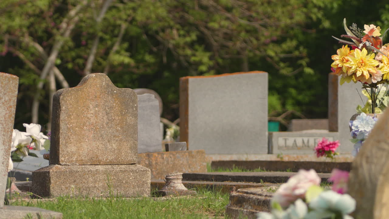 A serene graveyard scene with various headstones and artificial flowers