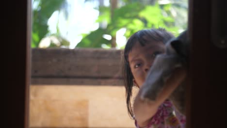 pretty little indonesian child helping mom around the house by washing the windows in a door