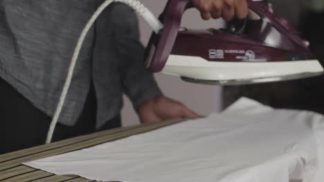 close up to young male hand steaming white shirt by steam iron