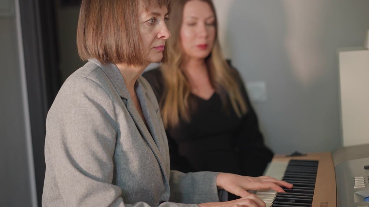 Wärme des Klavierunterrichts. Lehrer und Schüler teilen Musik. Ruhige Atmosphäre mit konzentrierten Händen auf den Tasten. Warme Beleuchtung verstärkt die intime Szene des Musikunterrichts und der geduldigen Anleitung.