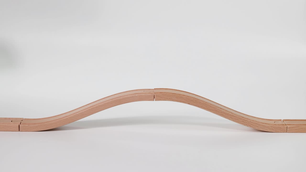 손은 물결 모양의 나무 트랙에서 장난감 차를 움직인다