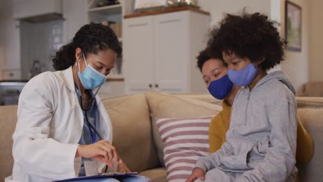 Mixed-race-female-doctor-wearing-mask-examining-mixed-race-girl-at-home