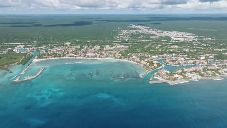 aerial view in dolly back of a coastal city, full of vibrant architecture and pristine beaches surrounded by the majestic sea in mexico