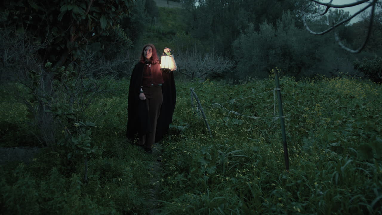 una mujer enigmática camina por el prado por la noche en un bosque embrujado.