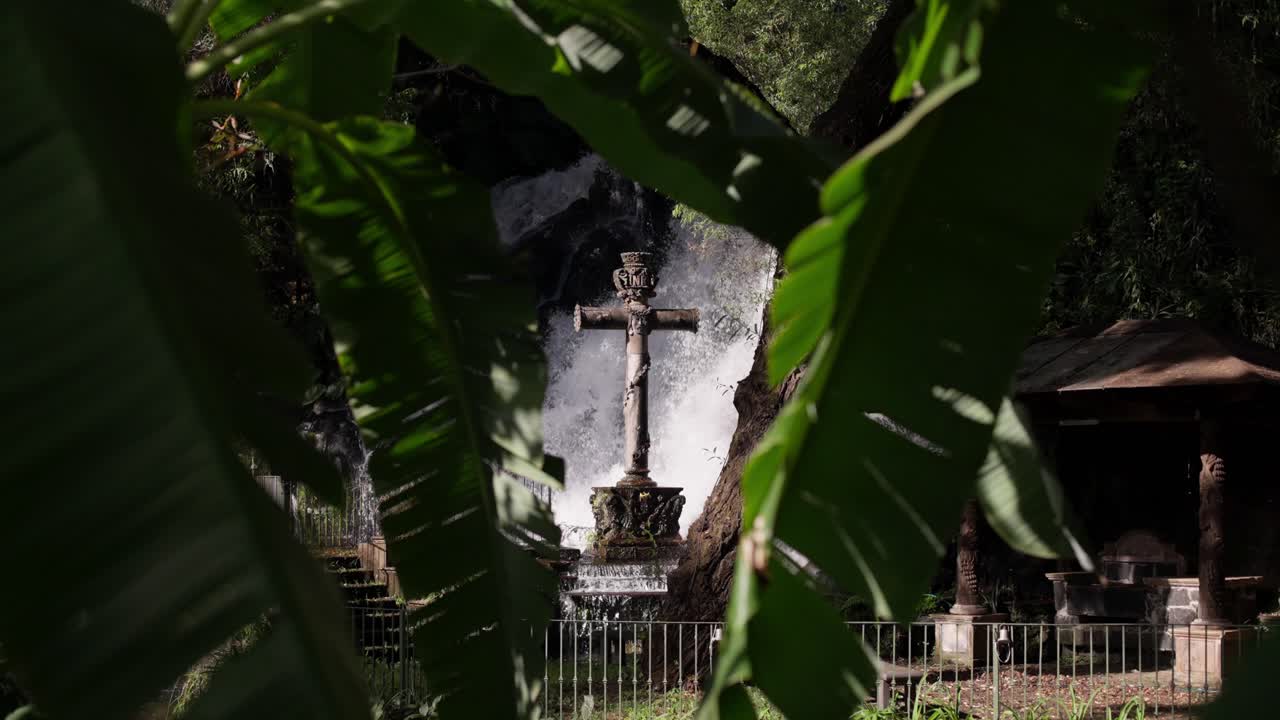 fotografía estática en cámara lenta de una gran cruz de piedra cerca de una cascada en uruapan michoacan al atardecer