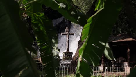 SLOW-MOTION-STATIC-SHOT-OF-A-BIG-STONE-CROSS-NEAR-A-WATERFALL-IN-URUAPAN-MICHOACAN-AT-SUNSET