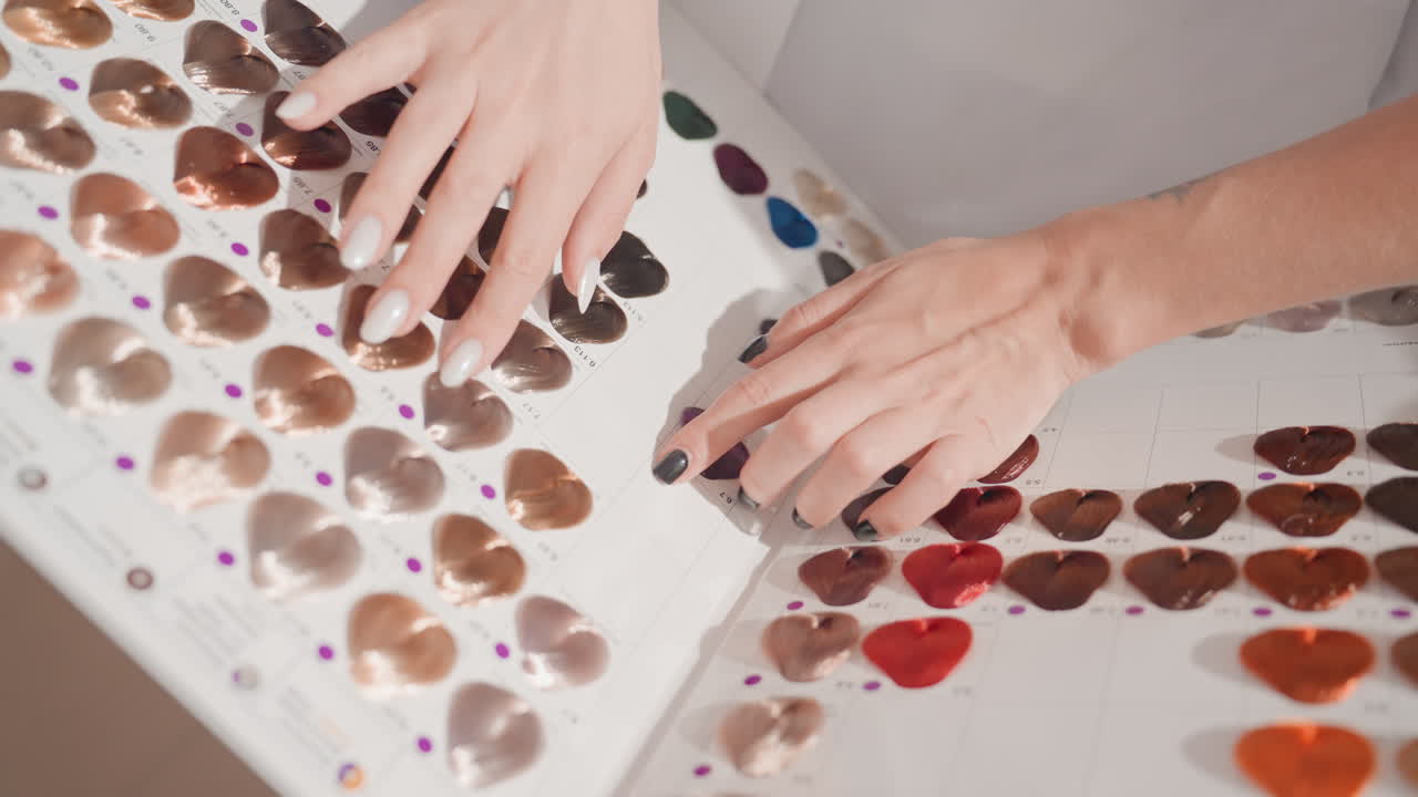 Hands selecting lipstick swatches on palette, makeup artist comparing shades, color consultant arranging testers, stylist matching tones to skin, product tester sampling textures, designer noting