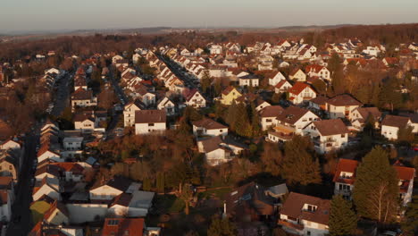 Forward-flying-drone-over-streets-with-family-houses-in-evening-light.-Tilting-up-and-heading-to-detail-of-several-houses.-Aerial-view.-Bad-Vilbel,-Germany.