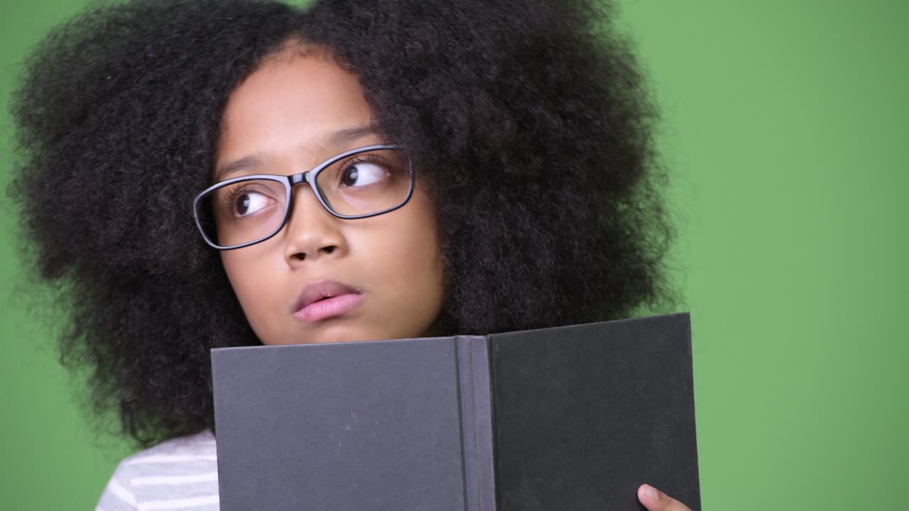 joven chica africana con cabello afro estudiando contra un fondo verde