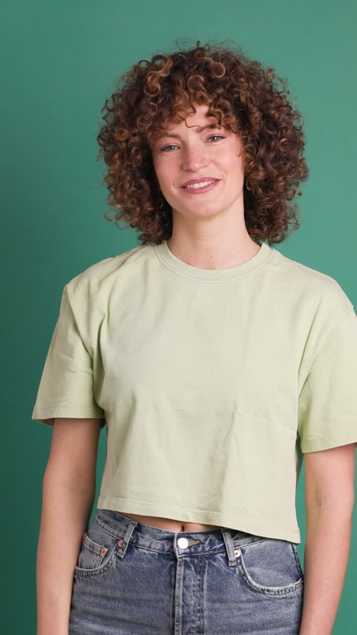 Adult woman on studio giving a thumbs up gesture. Vertical orientation