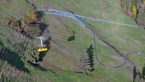 aerial shot of a cable car moving from the mountain down to the ground station on kronberg appenzell in the swiss alps