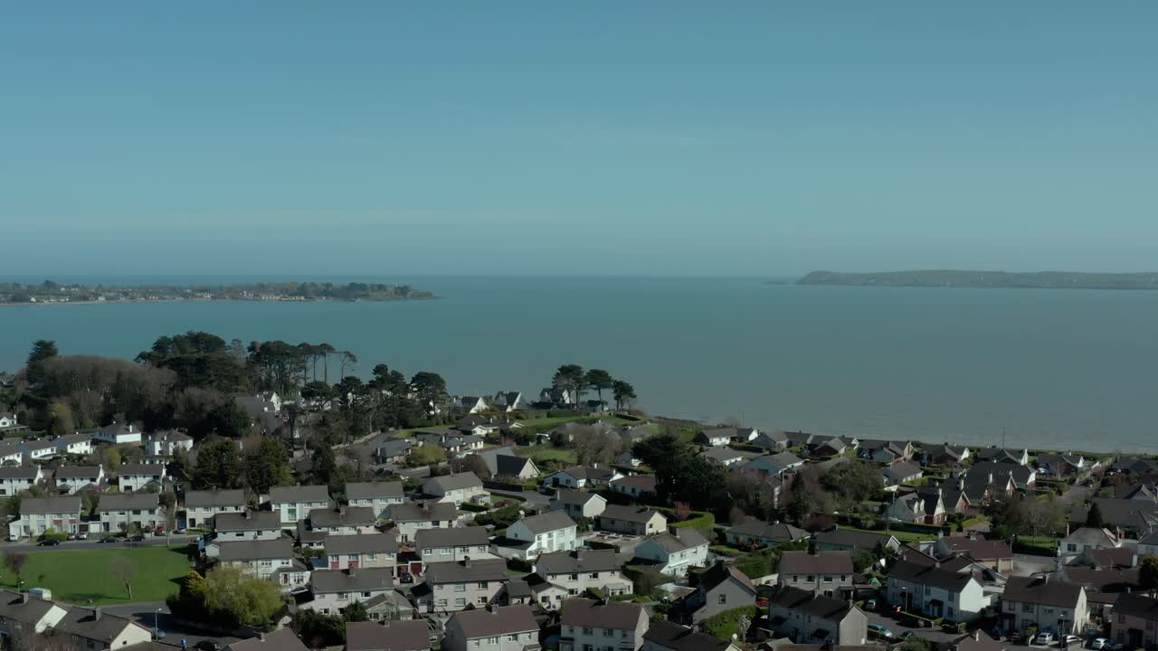 Vista aérea de sobrevoo sobre uma cidade perto do mar durante o dia no verão, com aproximação de câmera