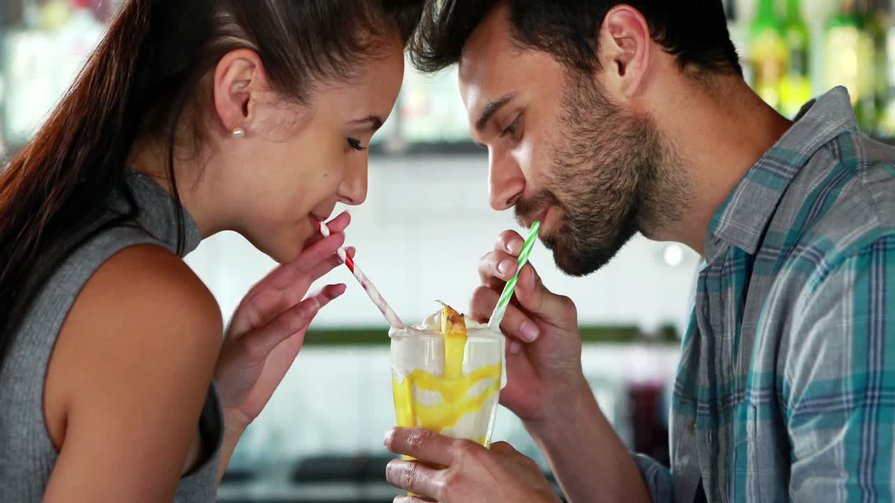 una pareja feliz compartiendo un batido de leche