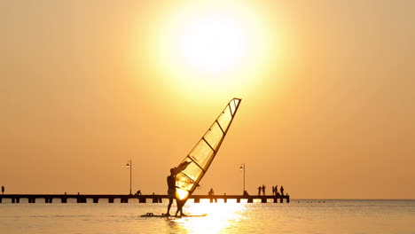 silhouette of surfer at sunset passing by