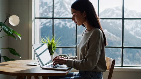young woman working on laptop at home with a mountain view