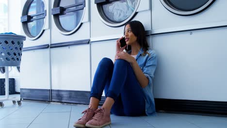 woman talking on mobile phone at laundromat 4k