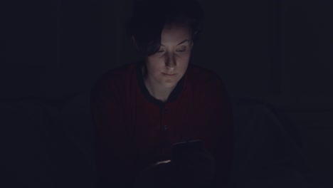 mujer usando teléfono móvil en la oscuridad