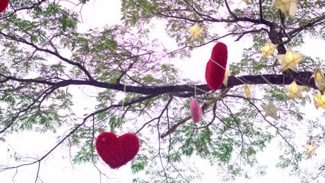 red hearts hanging on a tree with many paper stars and lights twinkling at night. valentine's day concept