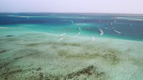 Kitesurfistas-Deslizándose-Sobre-Las-Aguas-Cristalinas-De-Cayo-Vapor,-Vibrante-Escena-Acuática,-Vista-Aérea