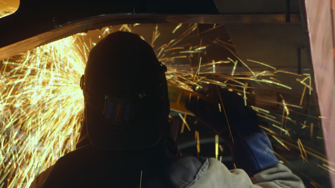 산업 노동자가 원형 톱으로 금속 부품을 정리하여 화려한 불꽃을 일으킵니다.