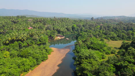 Beautiful-natural-scenery-of-river-amid-tropical-green-forest-with-mountains-in-background-Goa-India-4K-Drone