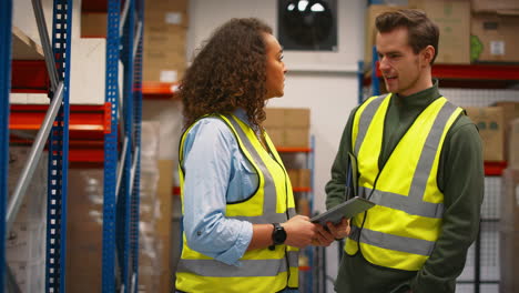 male and female workers with digital tablet in warehouse meeting and talking by shelves