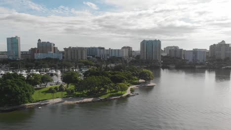 Hermosa-Antena-Matutina-Del-Centro-De-Sarasota,-Exuberante-Parque-Costero-Verde-Y-Puerto-Que-Alberga-Una-Envidiable-Cantidad-De-Grandes-Lanchas-Y-Yates