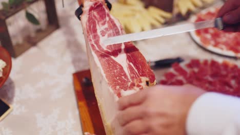 man cuts jamon into thin slices