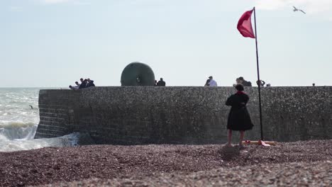 person walking by red flag on beach