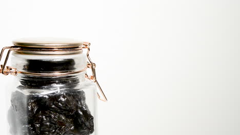 Dried-plums-in-an-airtight-mason-jar-rotating-on-a-white-background