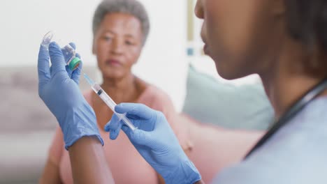mujer médica afroamericana llenando la jeringa del frasco de vial en casa