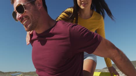 feliz pareja caucásica abrazada cerca de la playa buggy por el mar
