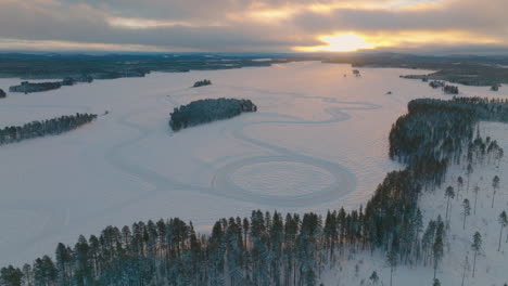 Goldener-Schneebedeckter-Sonnenaufgang-Und-Lange-Schatten-über-Dem-Lappländischen-Eissee-Treibende-Rennstreckenluftaufnahme