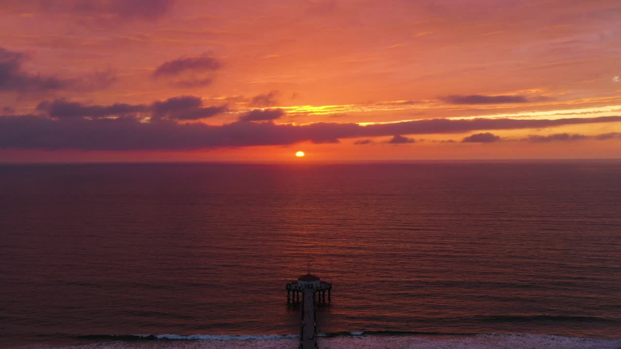 cielo rojo ardiente puesta de sol reflejada en el pacífico océano pacífico en el muelle de la playa de manhattan, california, ee.uu.