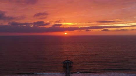 red fiery sky sunset reflected on peaceful pacific ocean in manhattan beach pier, california usa