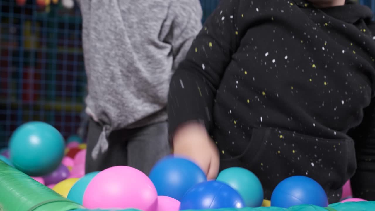 Happy children playing together and having fun at kindergarten with colorful balls. Slow motion