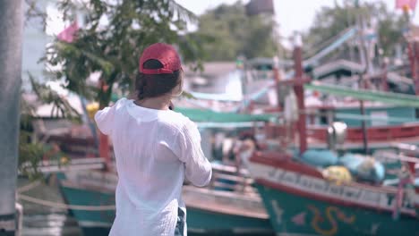 hermosa dama hace fotos de barcos con un teléfono inteligente negro