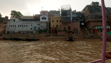 cinematic varanasi india ganges river canal boat cruise northern state gathering ancient holy city ghat pradesh province landscape gray cloudy afternoon muddy brown left