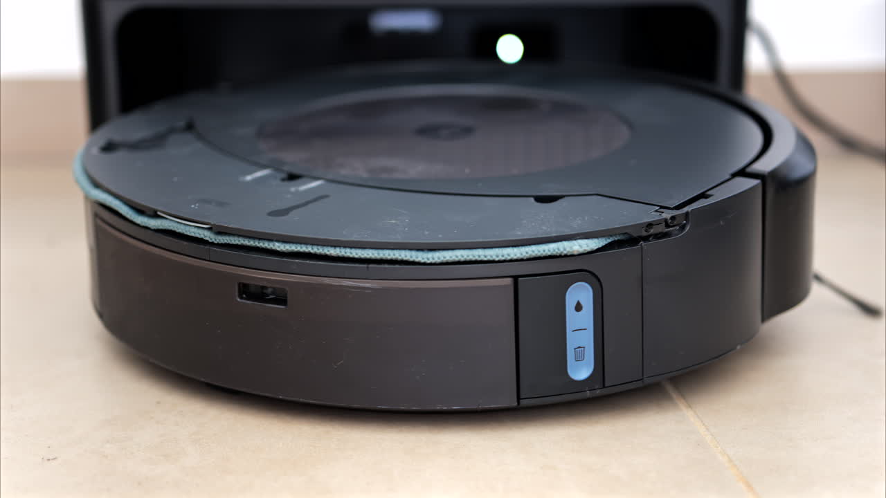 Close up of a black robot vacuum cleaner moving and rotating on the floor tiles