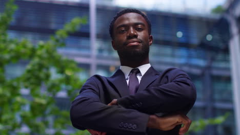 Portrait-Of-Confident-Young-Businessman-Wearing-Suit-Folding-Arms-Standing-Outside-Offices-In-The-Financial-District-Of-The-City-Of-London-UK-1